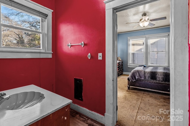 bathroom featuring ceiling fan, baseboards, and a sink