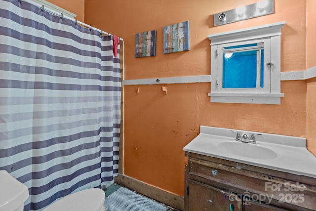 bathroom featuring toilet, vanity, and a shower with curtain