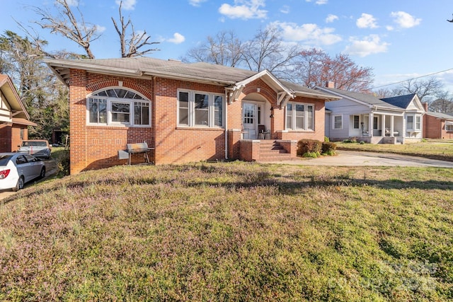 bungalow-style house with a front yard and brick siding