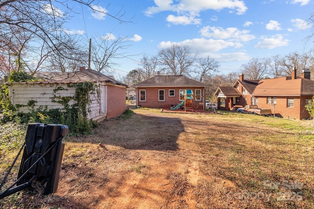 back of property with an outbuilding, a playground, and brick siding