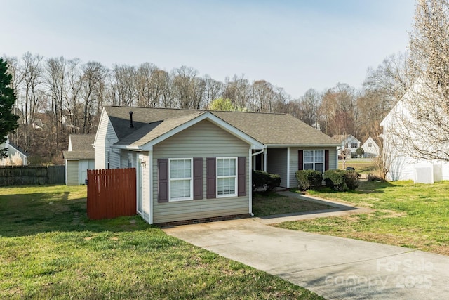 view of front of home with a shingled roof, a front yard, and fence