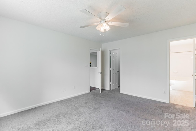 unfurnished bedroom featuring ensuite bath, carpet flooring, baseboards, and a textured ceiling