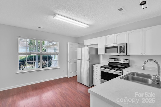 kitchen featuring visible vents, stainless steel appliances, dark wood-type flooring, and a sink