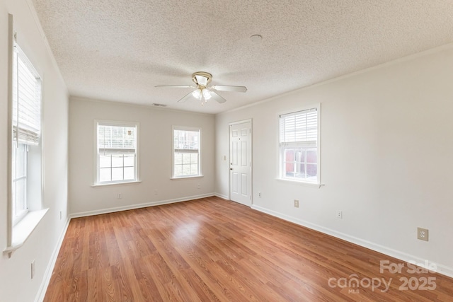 empty room with visible vents, a ceiling fan, a textured ceiling, light wood-style floors, and baseboards