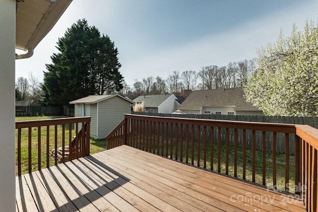 wooden deck featuring a storage shed, an outbuilding, a yard, and a fenced backyard