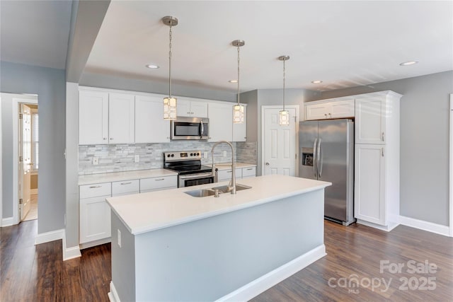 kitchen with an island with sink, dark wood-style flooring, appliances with stainless steel finishes, and a sink