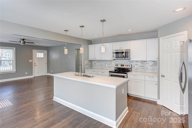 kitchen featuring dark wood-type flooring, decorative backsplash, appliances with stainless steel finishes, white cabinets, and a sink