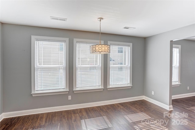 unfurnished dining area with visible vents, baseboards, and dark wood-style floors