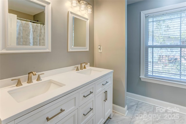 full bath featuring a sink, baseboards, marble finish floor, and double vanity