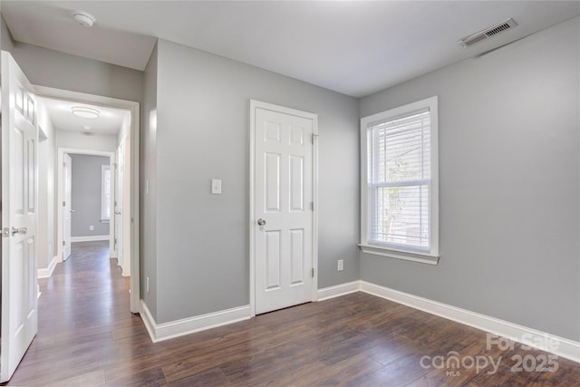 unfurnished bedroom featuring visible vents, baseboards, and dark wood-type flooring