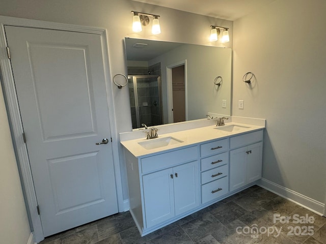 full bathroom featuring a sink, baseboards, double vanity, and a shower stall