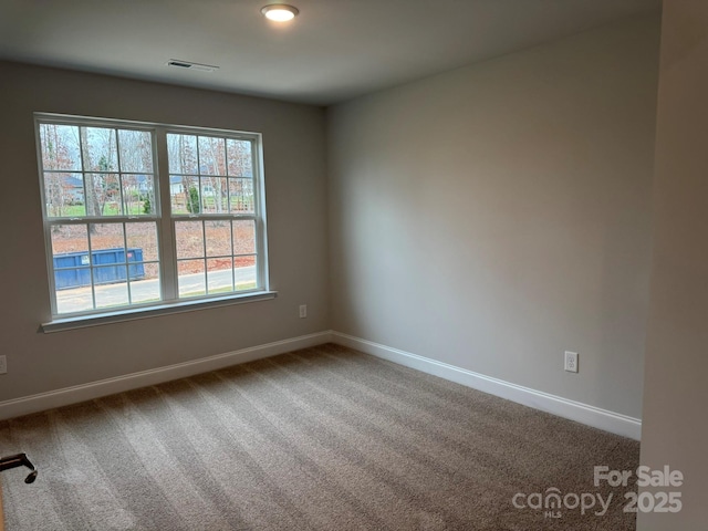 carpeted empty room featuring visible vents and baseboards