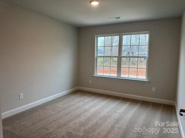 carpeted spare room featuring visible vents and baseboards