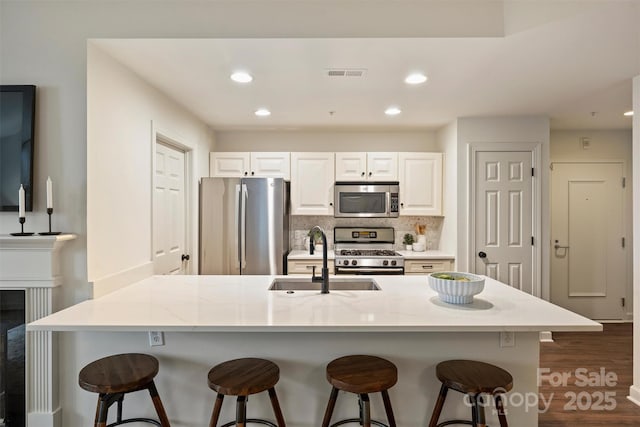 kitchen featuring a breakfast bar area, visible vents, a sink, appliances with stainless steel finishes, and tasteful backsplash