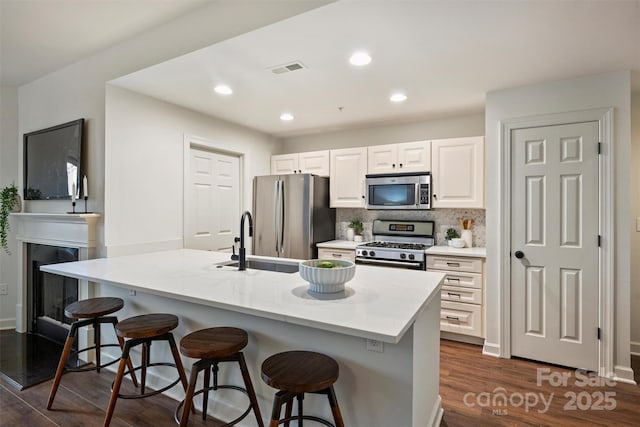 kitchen featuring a breakfast bar, dark wood finished floors, appliances with stainless steel finishes, and a sink