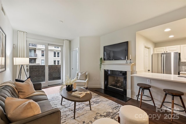 living room featuring a high end fireplace, recessed lighting, baseboards, and dark wood-style flooring