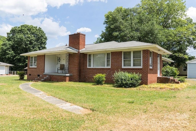 view of front facade featuring a chimney, a front yard, a porch, and brick siding