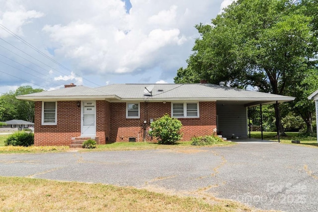 ranch-style house with a chimney, brick siding, aphalt driveway, and a carport