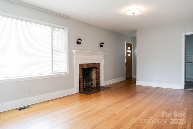 unfurnished living room featuring visible vents, light wood-style flooring, and baseboards