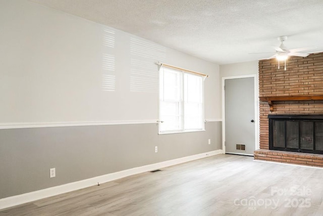 unfurnished living room with a textured ceiling, baseboards, wood finished floors, and a ceiling fan