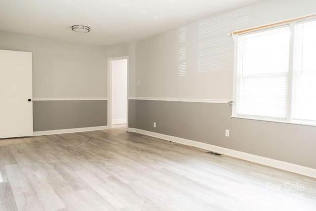 spare room with baseboards, visible vents, and wood finished floors