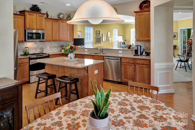 kitchen with a breakfast bar, a sink, tasteful backsplash, stainless steel appliances, and light countertops