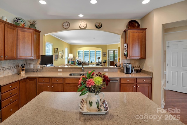 kitchen featuring a sink, light stone countertops, stainless steel dishwasher, and brown cabinetry