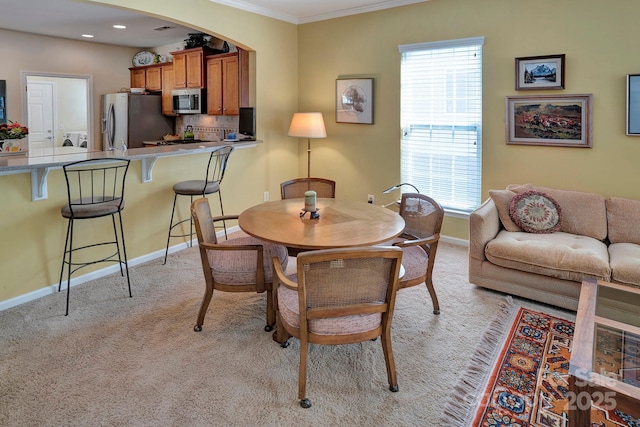 dining area with light carpet, a healthy amount of sunlight, baseboards, and ornamental molding