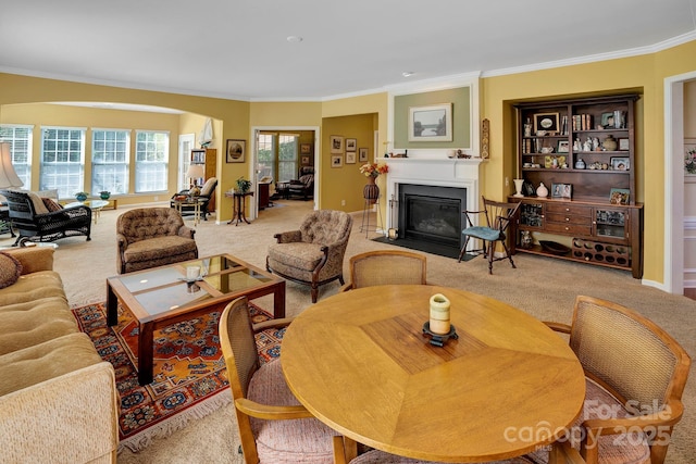 living room with baseboards, carpet floors, arched walkways, ornamental molding, and a large fireplace