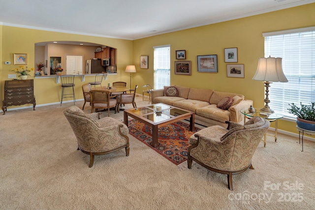 carpeted living room with baseboards, arched walkways, a healthy amount of sunlight, and crown molding