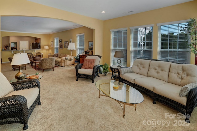 carpeted living area featuring arched walkways, visible vents, and recessed lighting