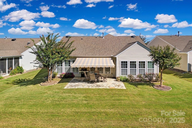 rear view of house with a patio, a lawn, and a shingled roof