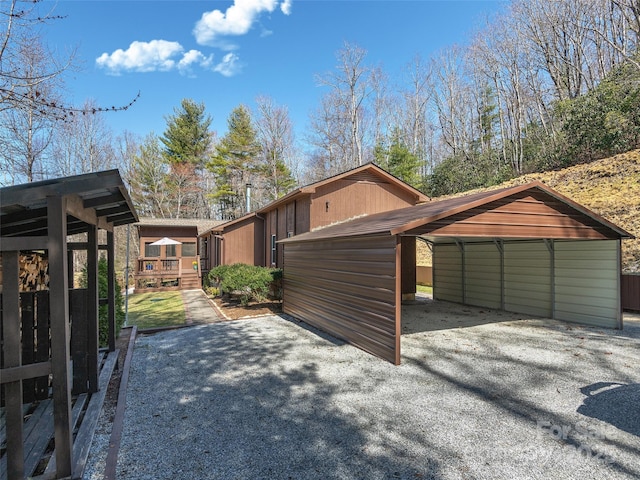 view of side of home with a wooden deck, a detached carport, and driveway