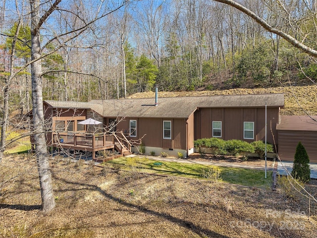 back of house with a deck and roof with shingles