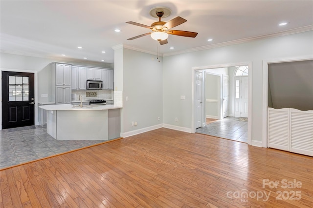 kitchen with ceiling fan, light countertops, light wood-style floors, and stainless steel appliances