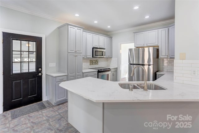 kitchen with light stone counters, a peninsula, a sink, stainless steel appliances, and crown molding