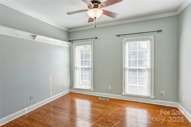 empty room featuring a wealth of natural light, visible vents, and hardwood / wood-style flooring