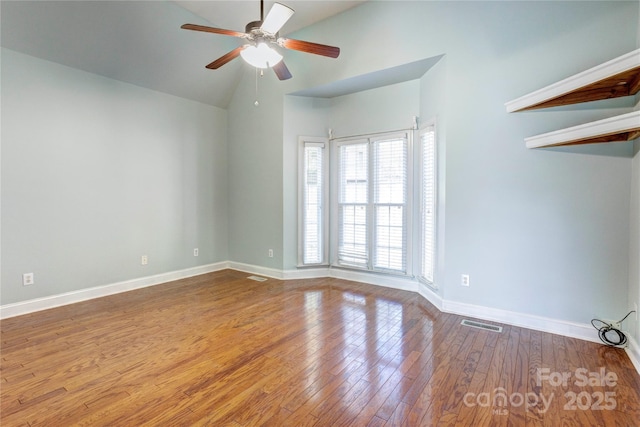 empty room with a ceiling fan, visible vents, baseboards, lofted ceiling, and hardwood / wood-style flooring