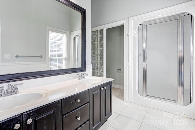 full bathroom with tile patterned floors, double vanity, a shower stall, and a sink