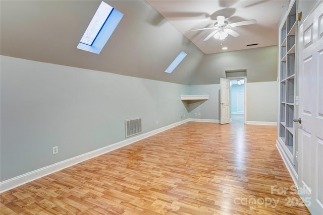 bonus room featuring visible vents, lofted ceiling with skylight, light wood finished floors, baseboards, and ceiling fan