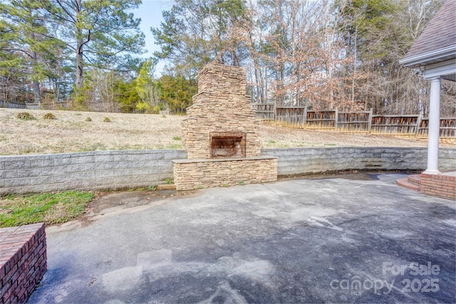 view of patio with fence and an outdoor stone fireplace