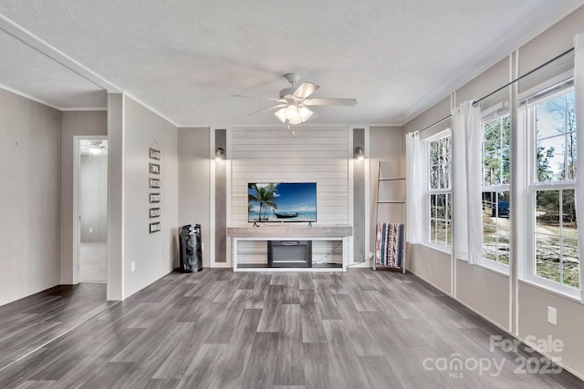 unfurnished living room with a wealth of natural light, ceiling fan, and wood finished floors