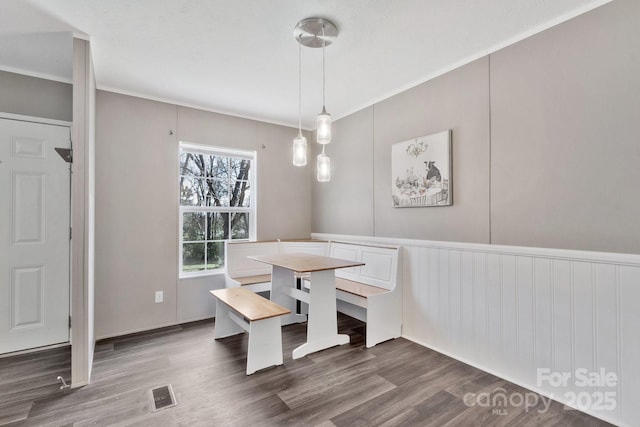 dining area with visible vents, wood finished floors, and a decorative wall