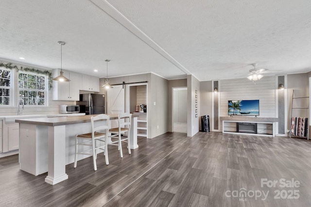kitchen with stainless steel microwave, a center island, open floor plan, a barn door, and freestanding refrigerator