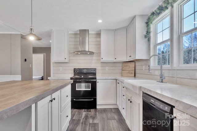 kitchen featuring a sink, black appliances, light countertops, wall chimney exhaust hood, and backsplash