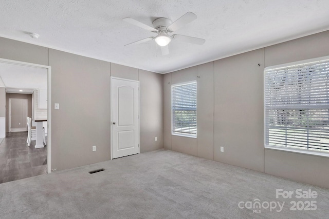unfurnished bedroom featuring visible vents, a textured ceiling, ceiling fan, and carpet floors