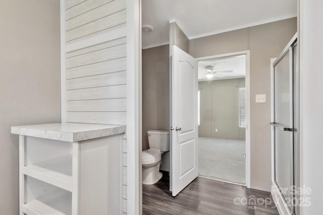 full bath with toilet, a shower stall, wood finished floors, and a ceiling fan