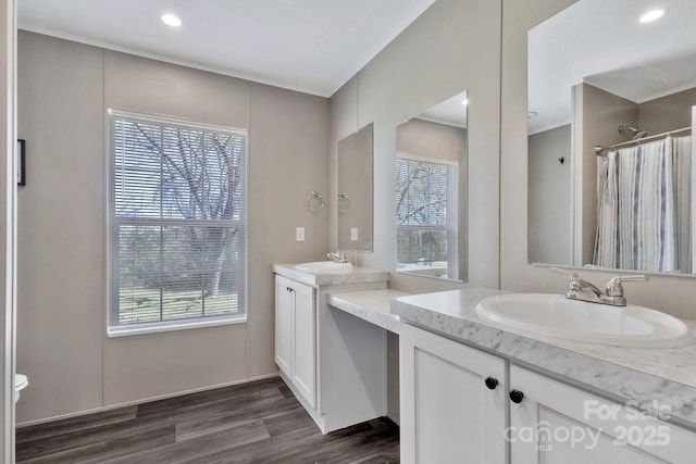 full bath with a shower with curtain, two vanities, wood finished floors, and a sink