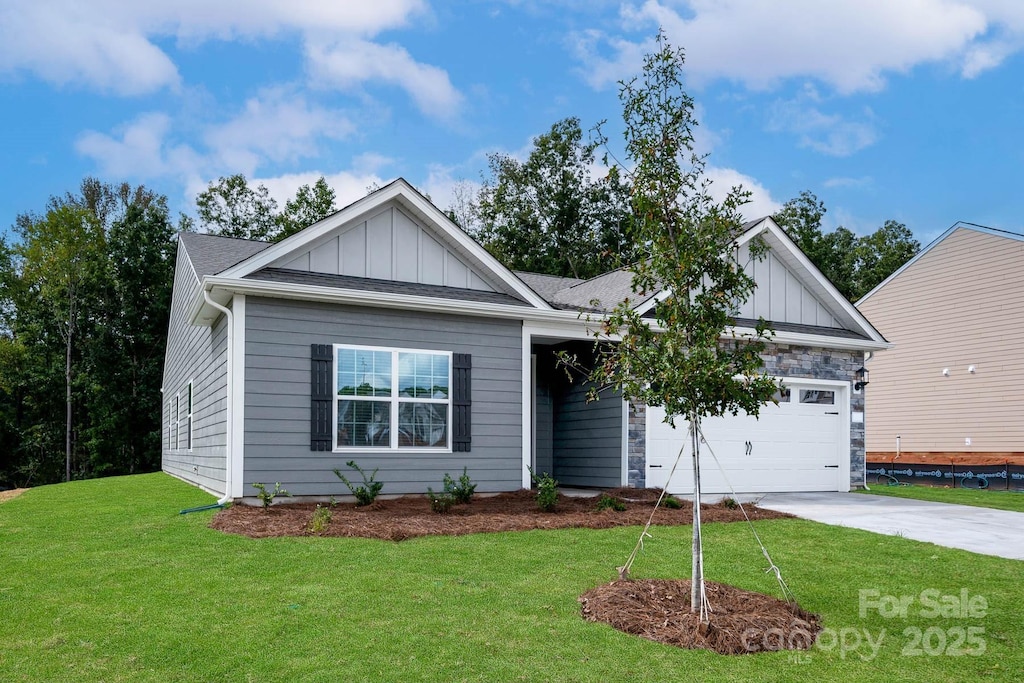 view of front of house featuring board and batten siding, concrete driveway, a front yard, stone siding, and an attached garage
