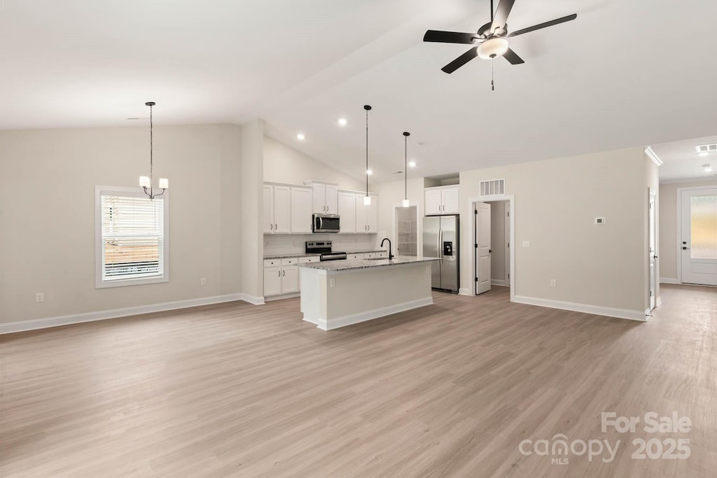 kitchen with open floor plan, an island with sink, light wood-style floors, stainless steel appliances, and a sink